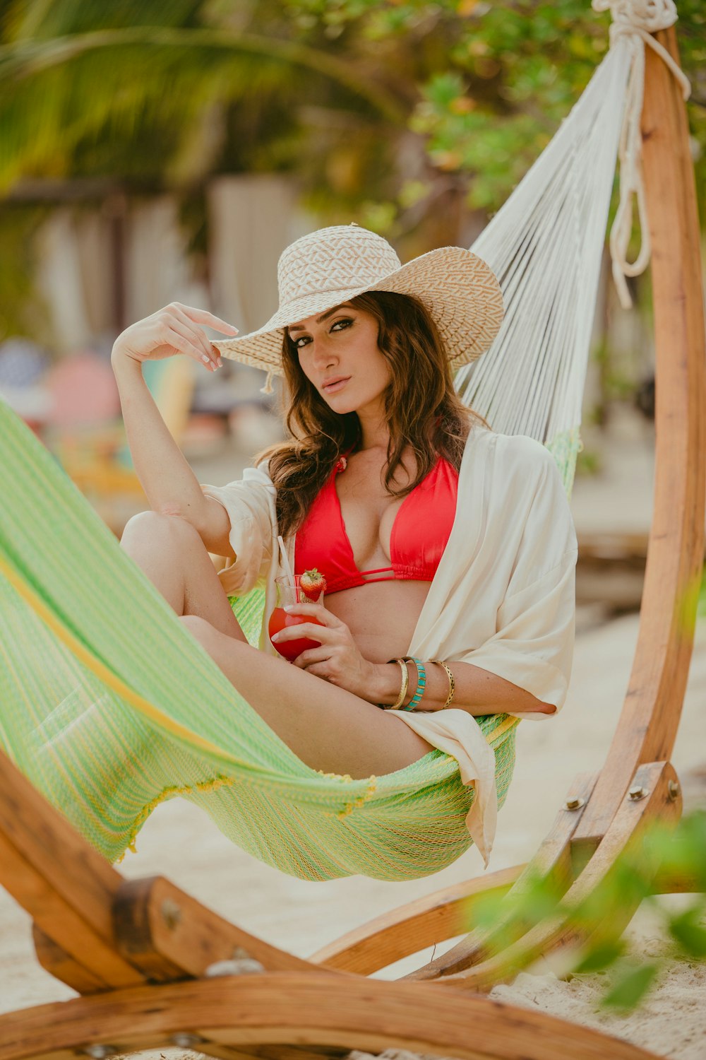 woman in red bikini wearing brown straw hat sitting on hammock