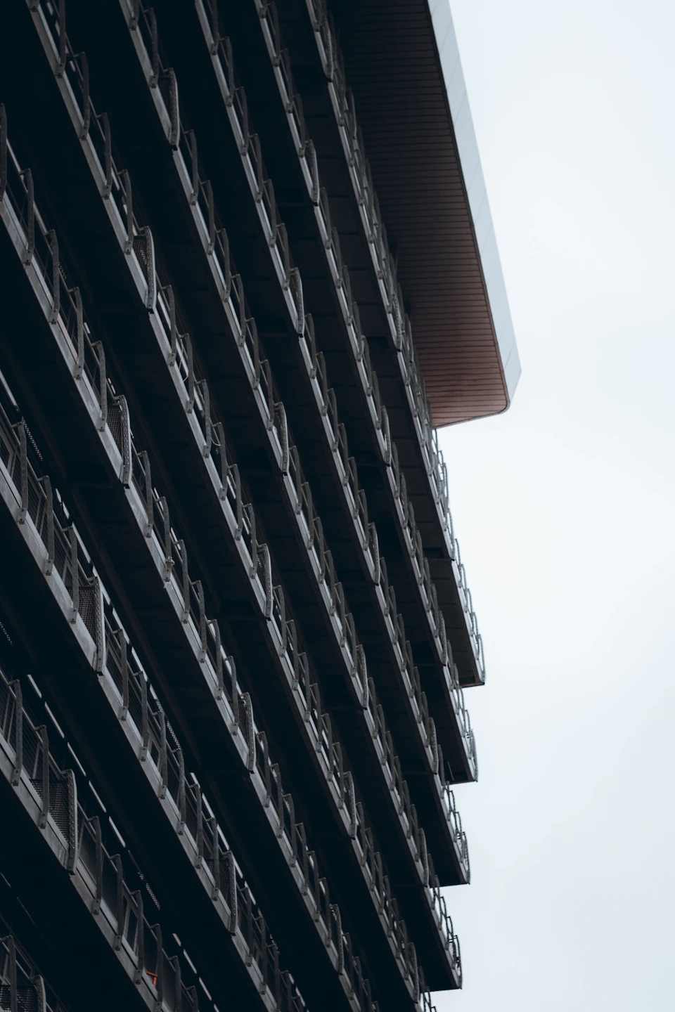 Tall modern building with multiple balconies and railings in dark-colored metal construction