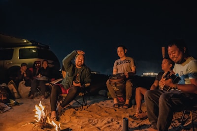 group of people sitting on brown wooden log during night time