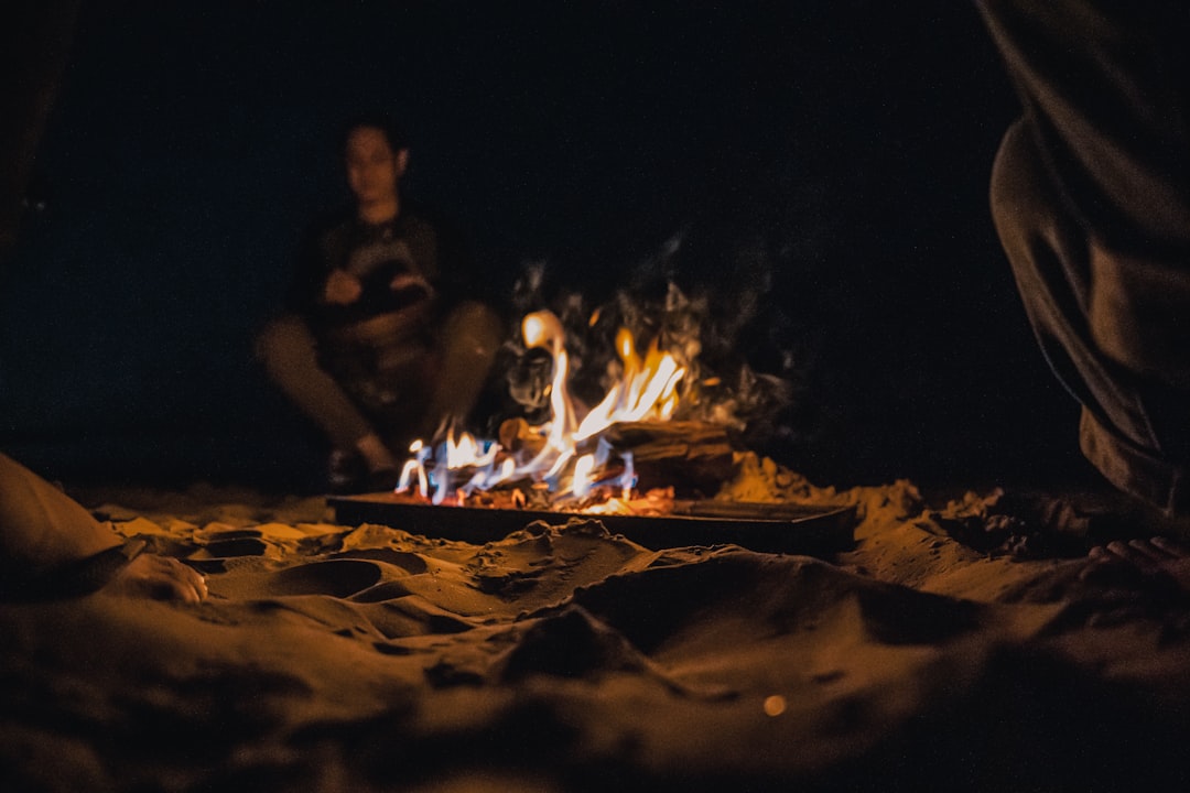 people sitting on ground with bonfire during night time