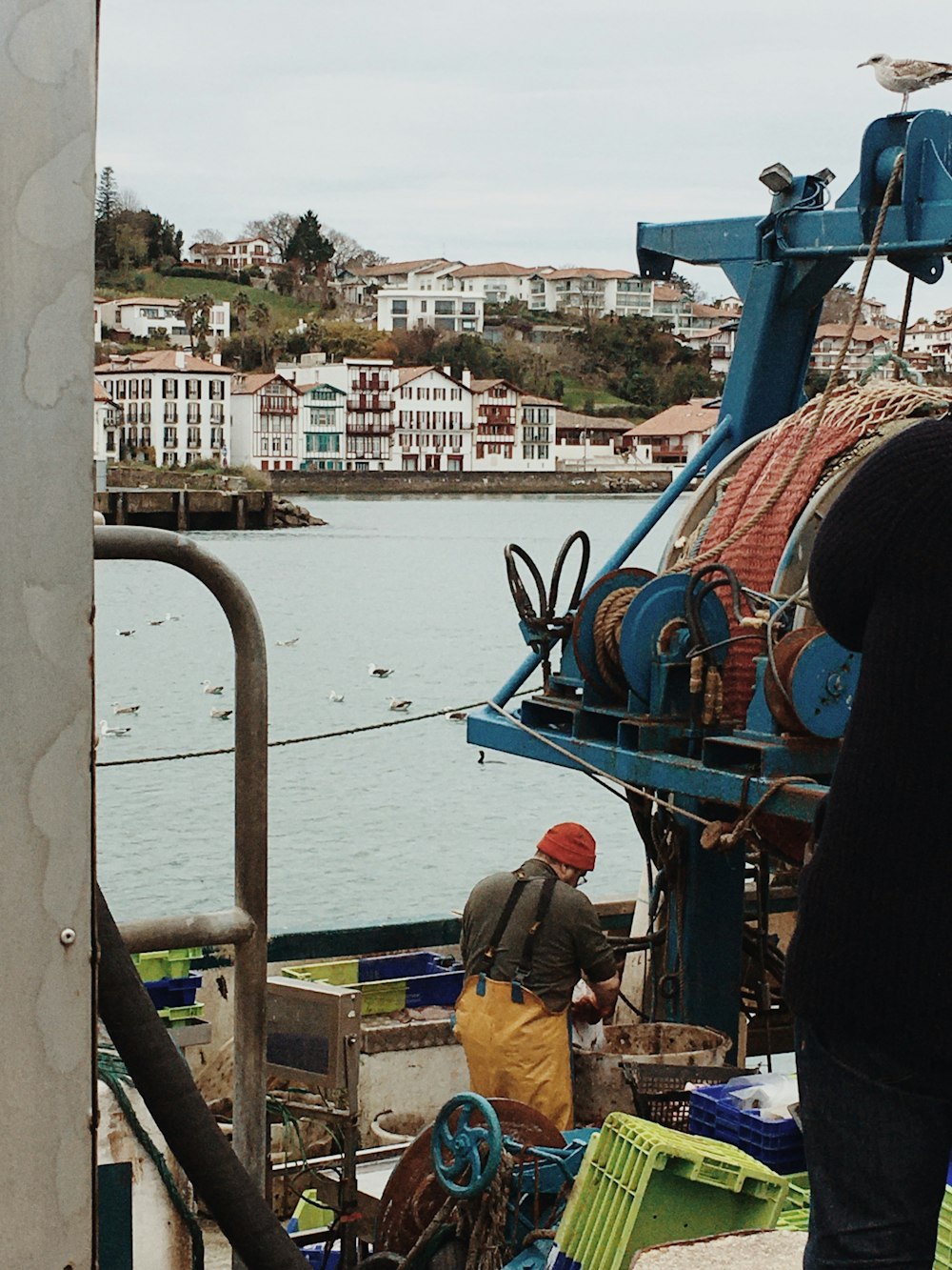 man in brown jacket standing beside blue and white boat during daytime