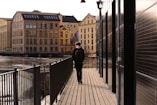 man in black jacket walking on wooden bridge during daytime