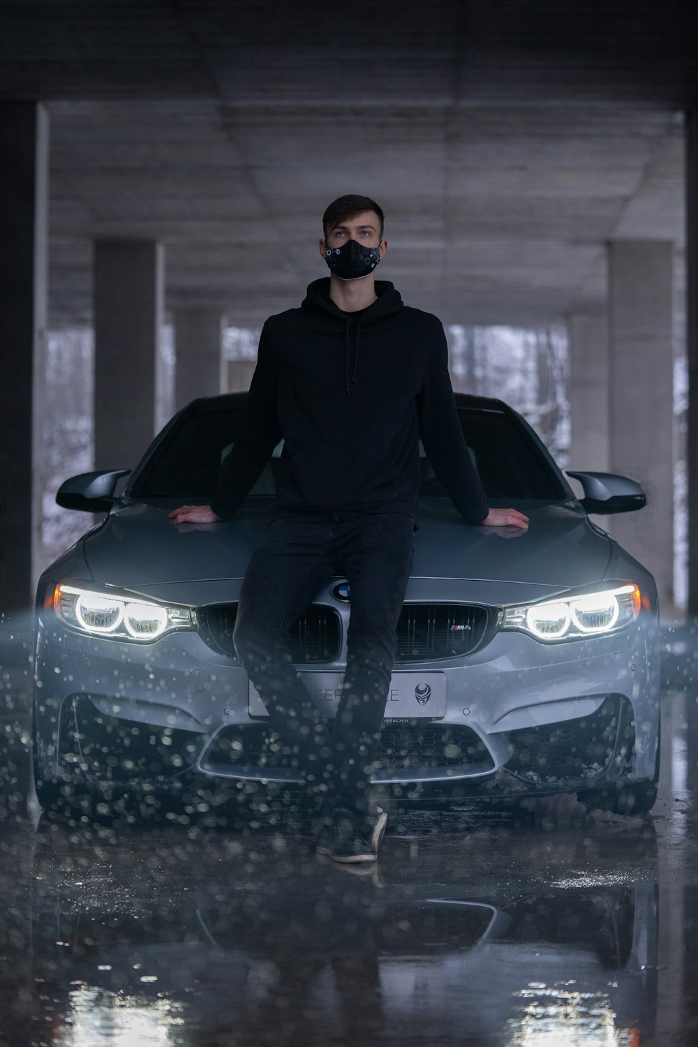 man in black hoodie riding black bmw car