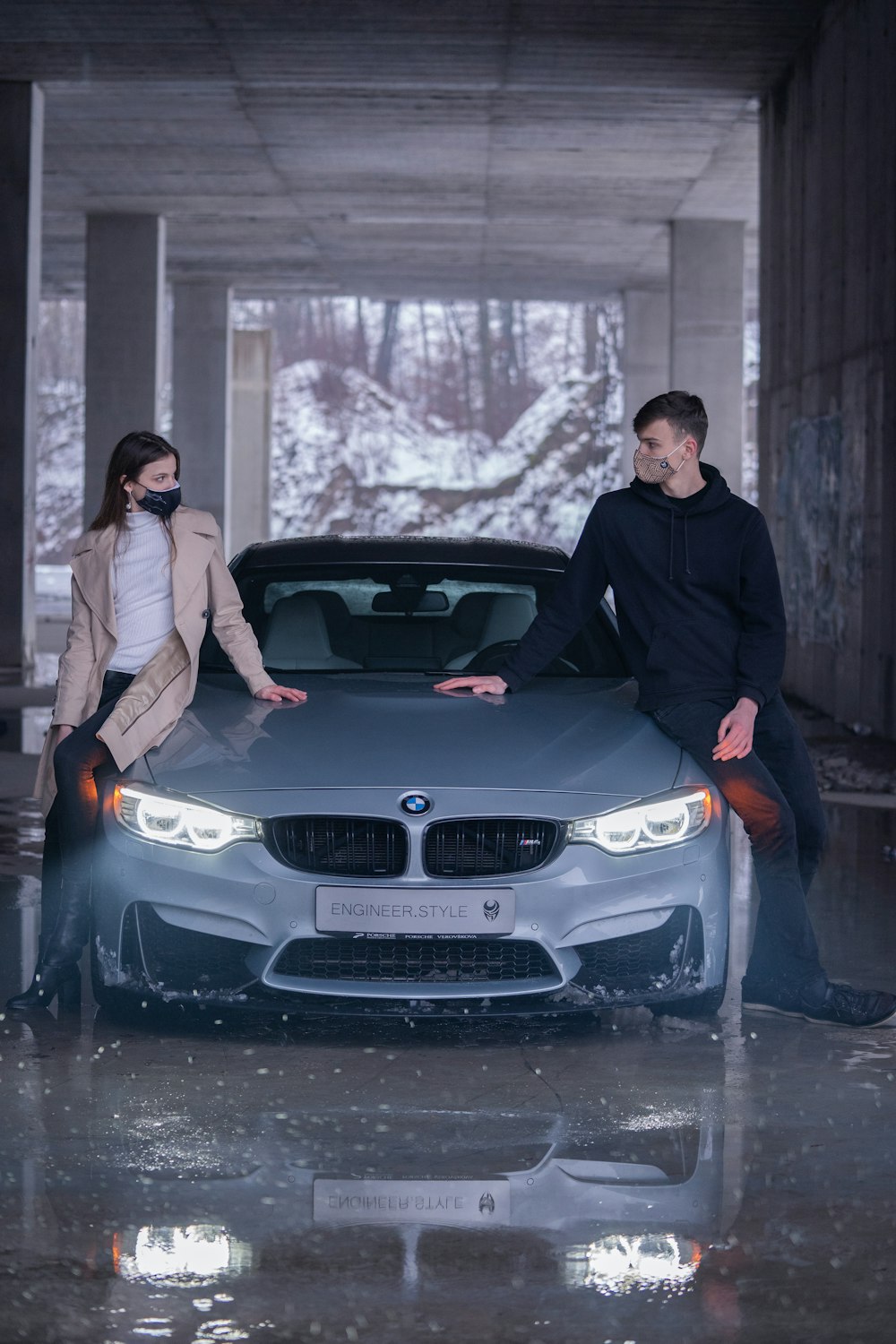 Homme en veste noire et jean en jean bleu assis sur une voiture BMW noire