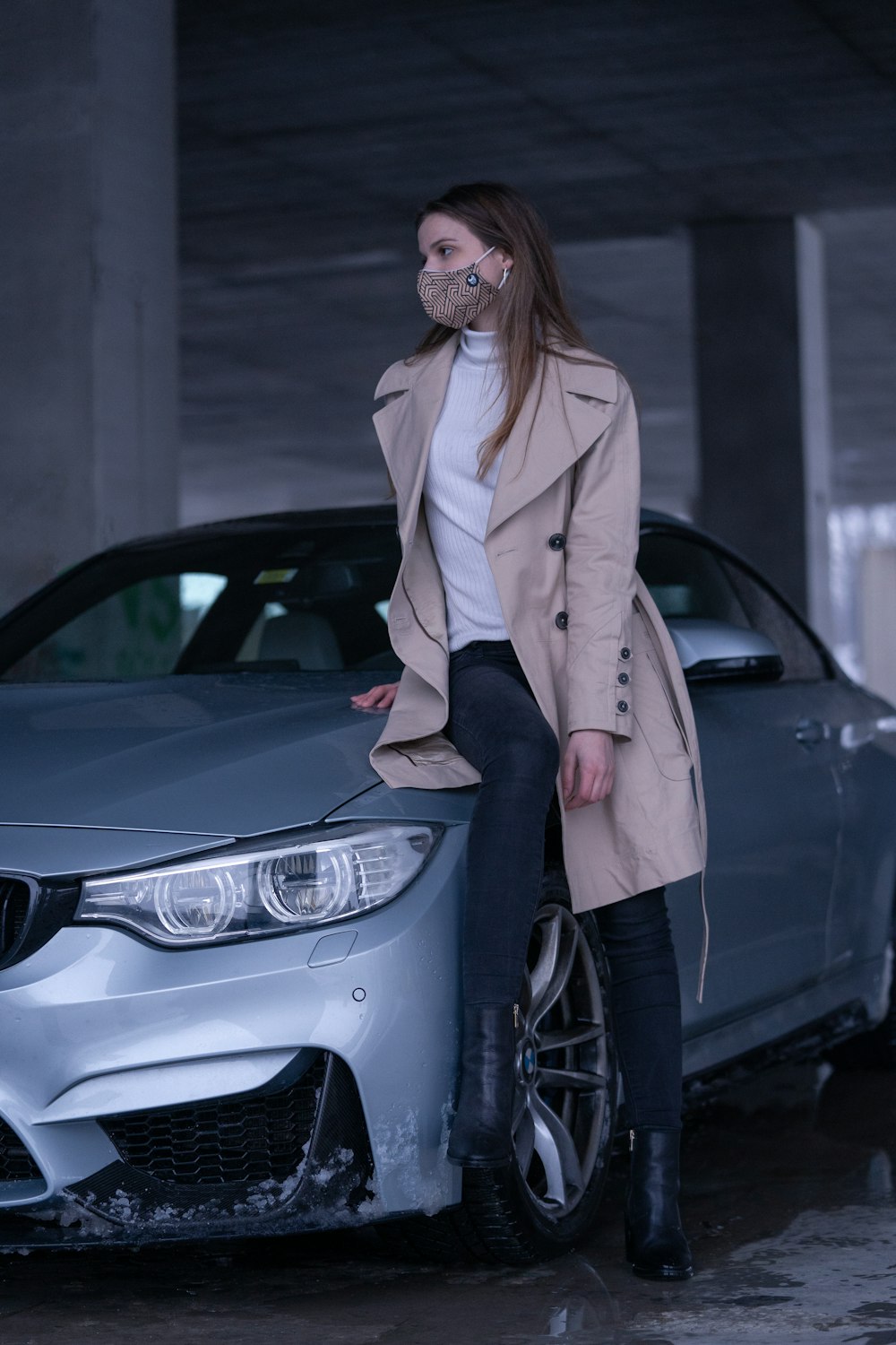 woman in white coat standing beside black car
