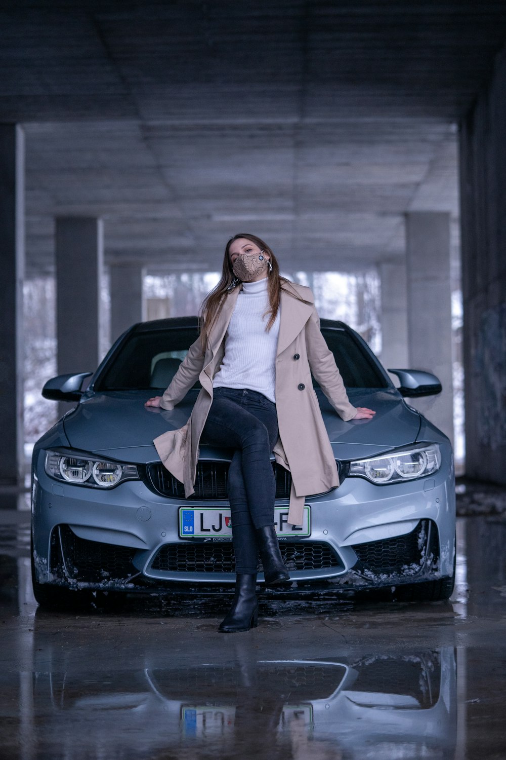 Mujer con cardigan blanco y jeans vaqueros azules sentada en un coche negro