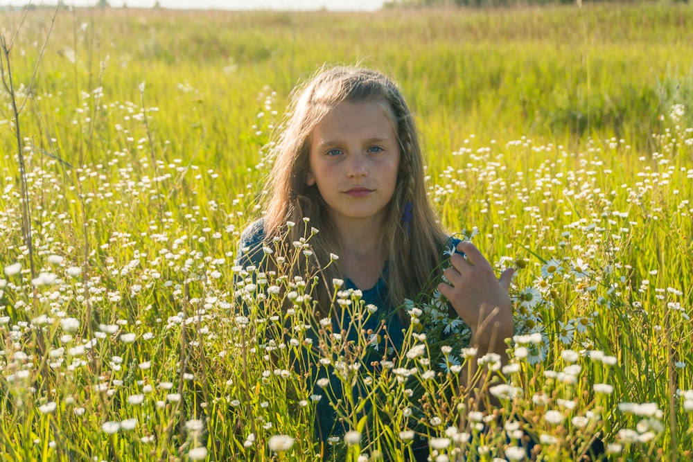 girl in blue and white floral dress standing on yellow flower field during daytime