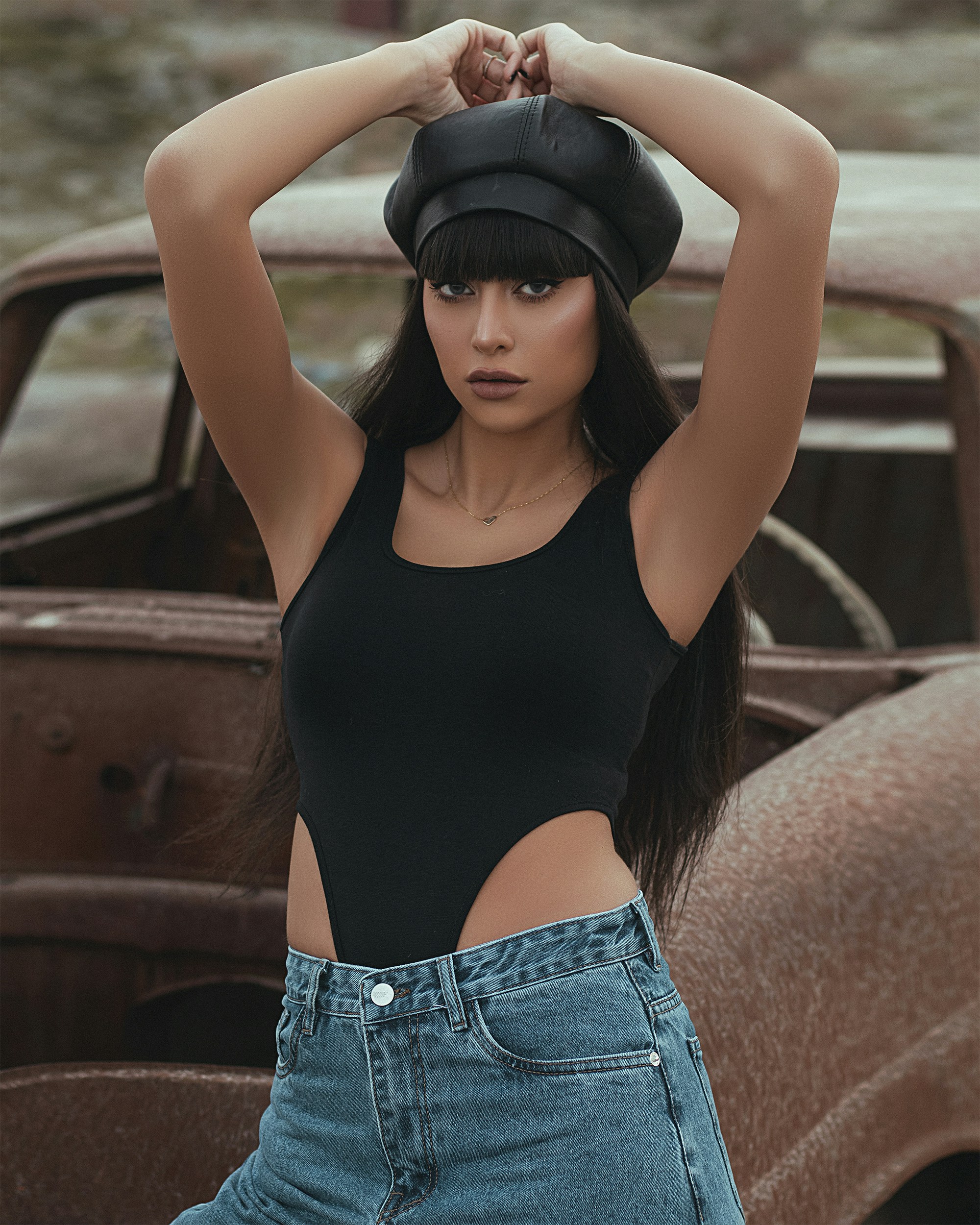 femme en débardeur noir et short en jean bleu portant un chapeau noir