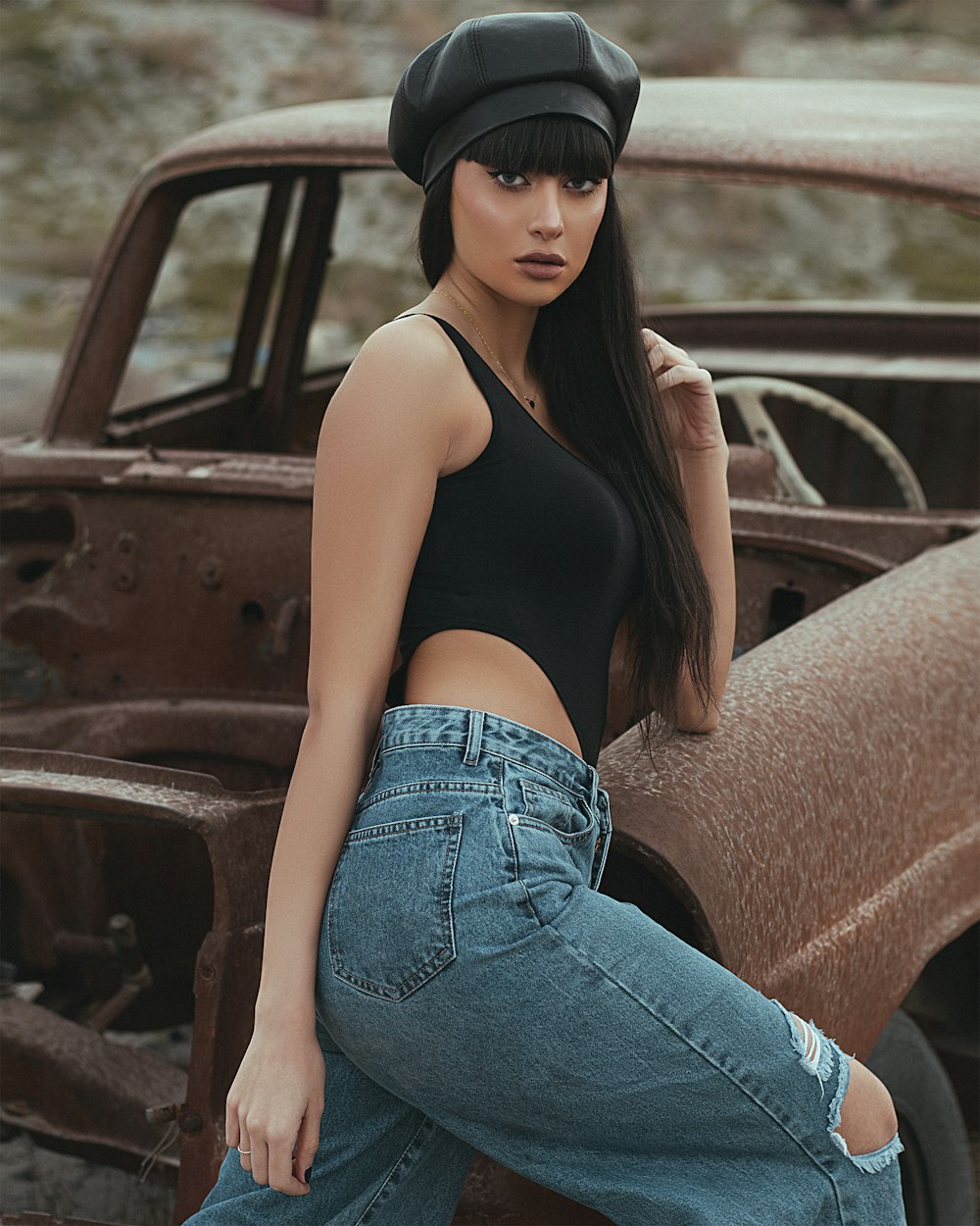 woman in black tank top and blue denim jeans sitting on brown car