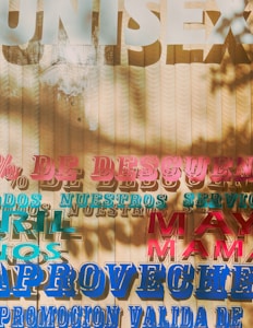 A textured background with layered, colorful text in various fonts and sizes. The words are written in Spanish, mentioning discounts and promotions. Shadows of leaves create an artistic overlay on the surface.