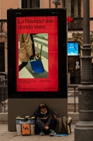 man in brown coat and blue denim jeans sitting on black metal bench