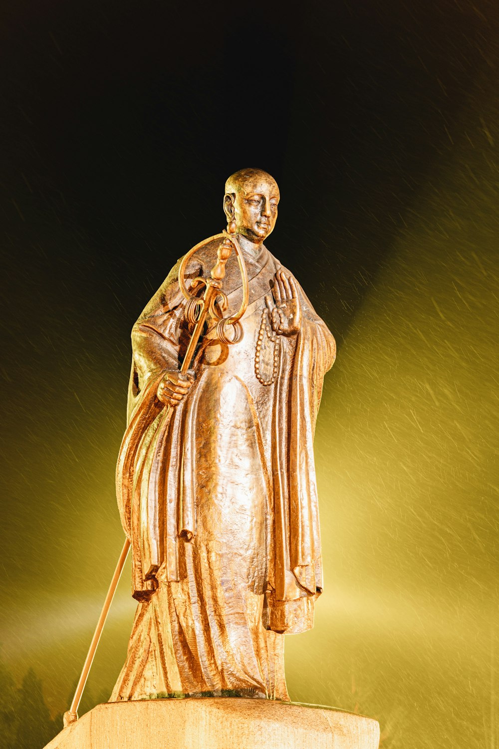 gold statue of man holding stick