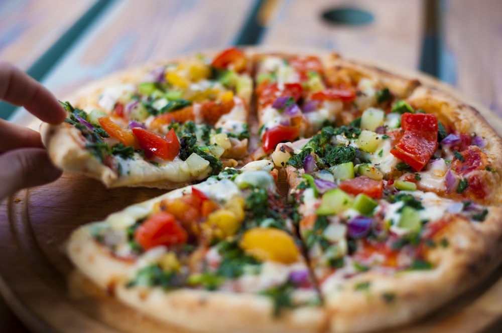 pizza with green and red bell pepper and cheese on brown wooden table