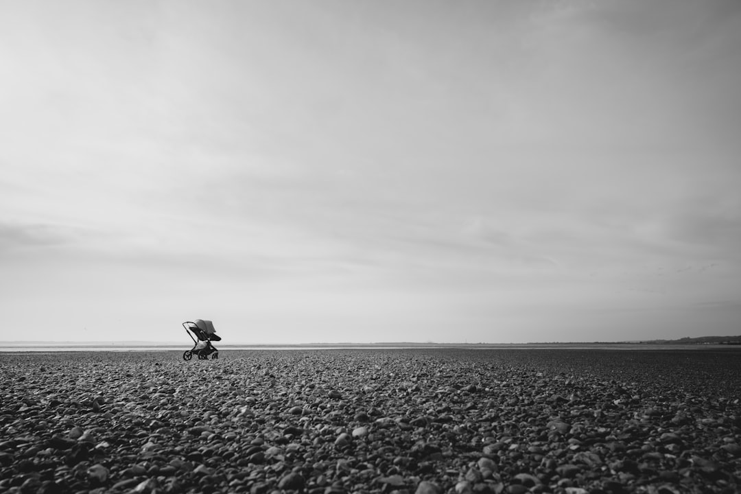 grayscale photo of person walking on the beach