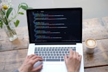 person using macbook pro on brown wooden table