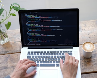 person using macbook pro on brown wooden table