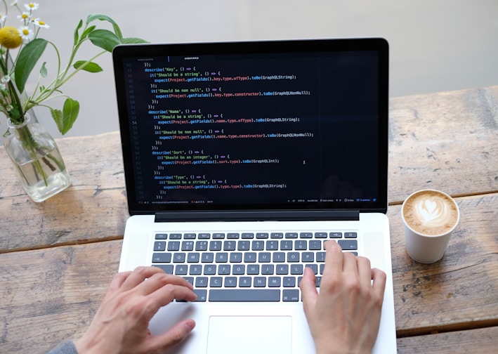 person using macbook pro on brown wooden table