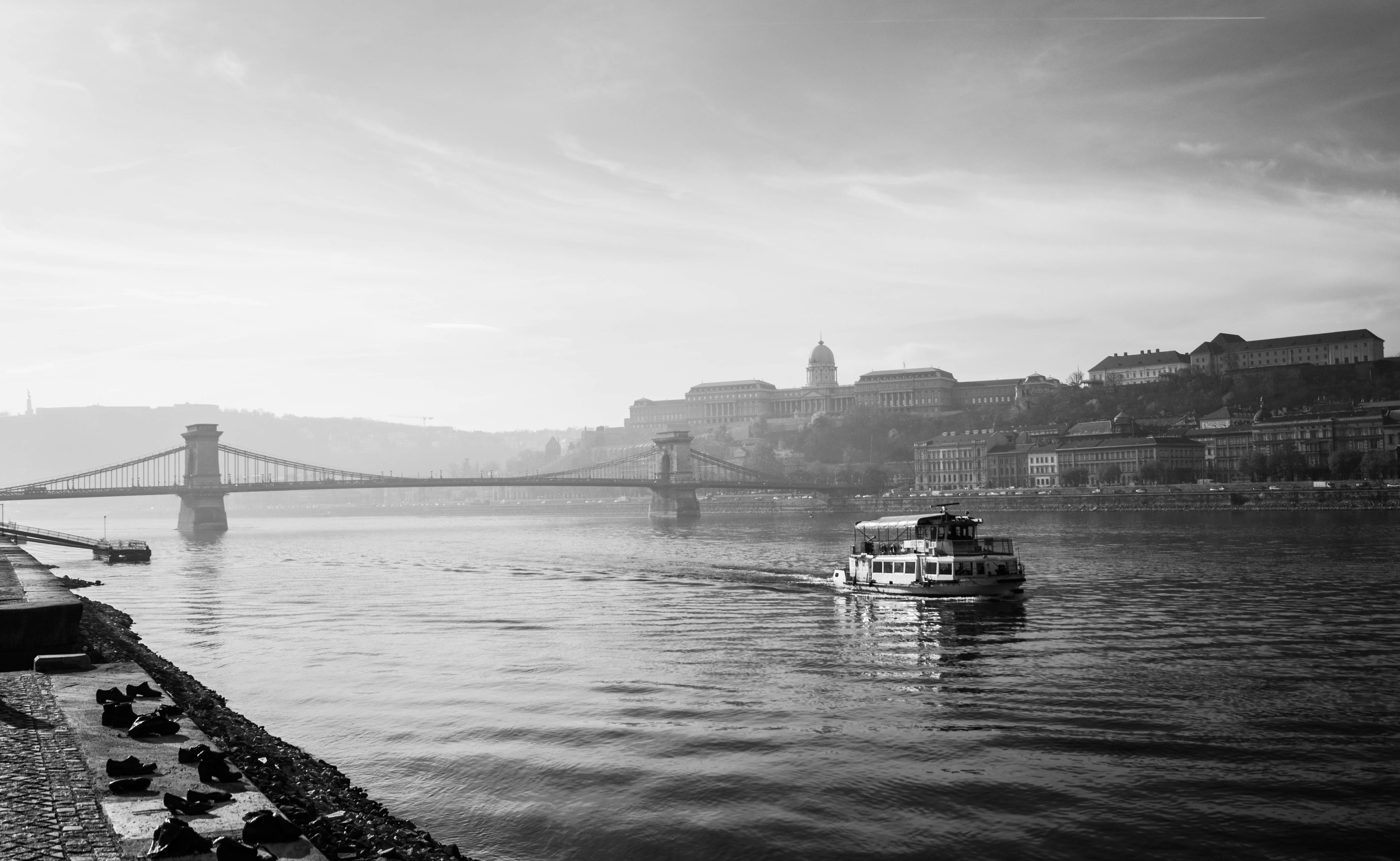 Graustufenfoto eines Bootes auf dem Wasser in der Nähe von Stadtgebäuden
