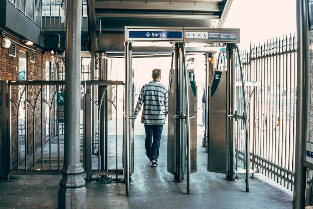 Mann im blau-weiß karierten Hemd steht auf dem Bahnhof