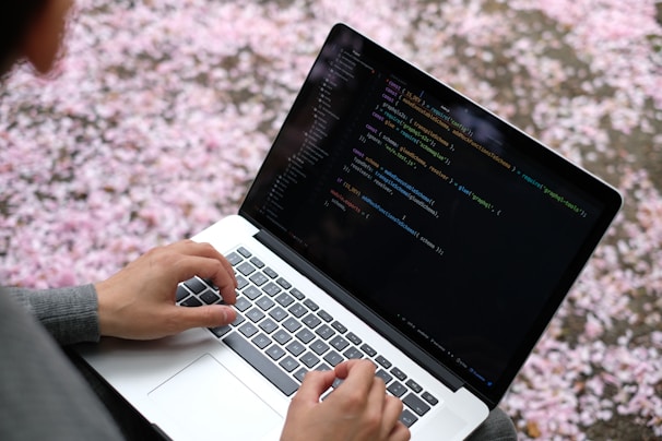 person using macbook pro on pink and white floral textile