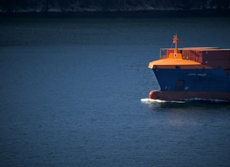 orange and white boat on blue sea during daytime