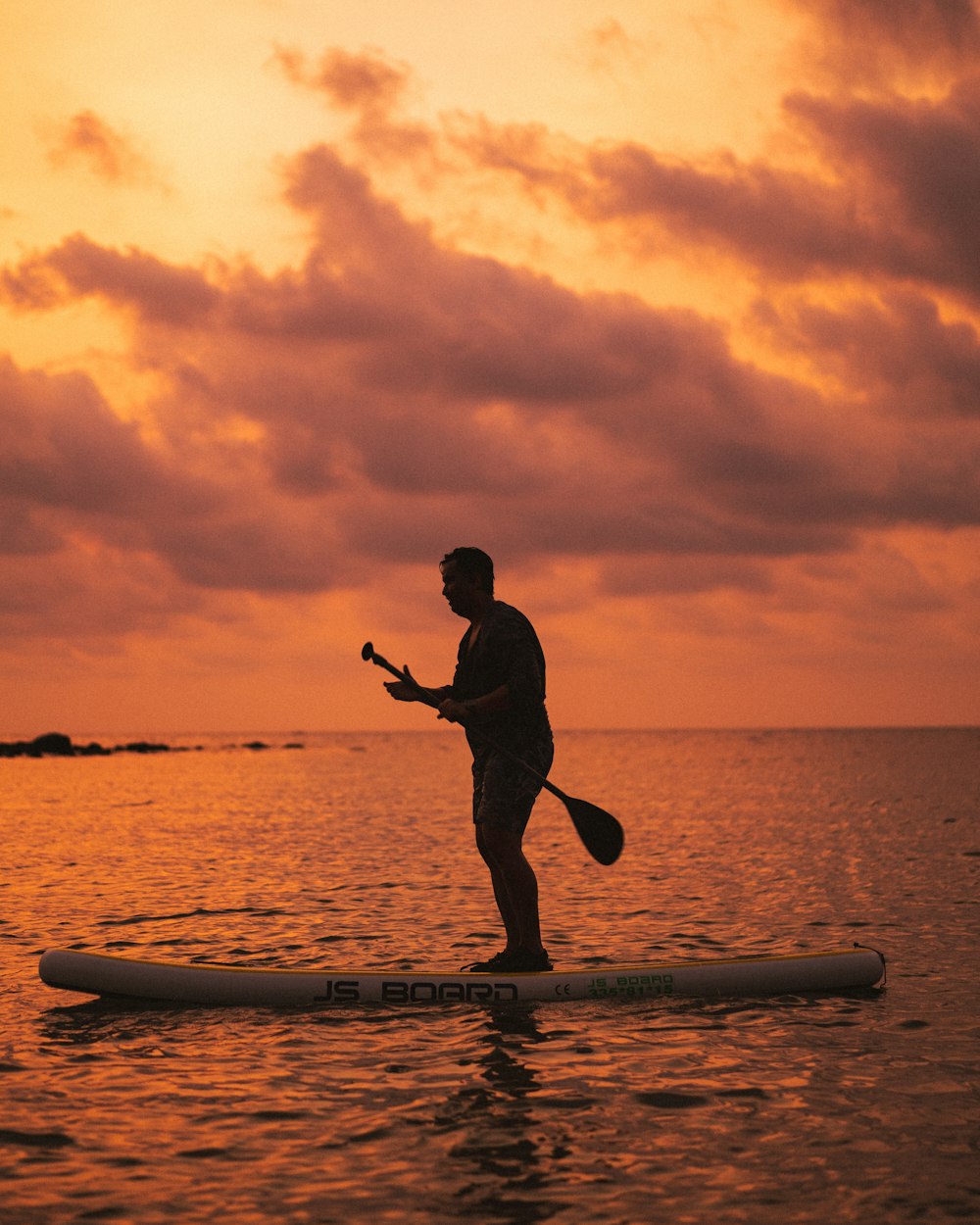 silhouette of man riding on surfboard during sunset