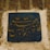 Arabic calligraphy with elegantly curved letters on a deep blue ceramic tile, set into a weathered stone wall.