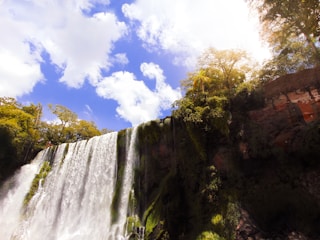 Una foto vibrante de las Cataratas del Iguazú rodeadas de un exuberante bosque bajo un cielo soleado