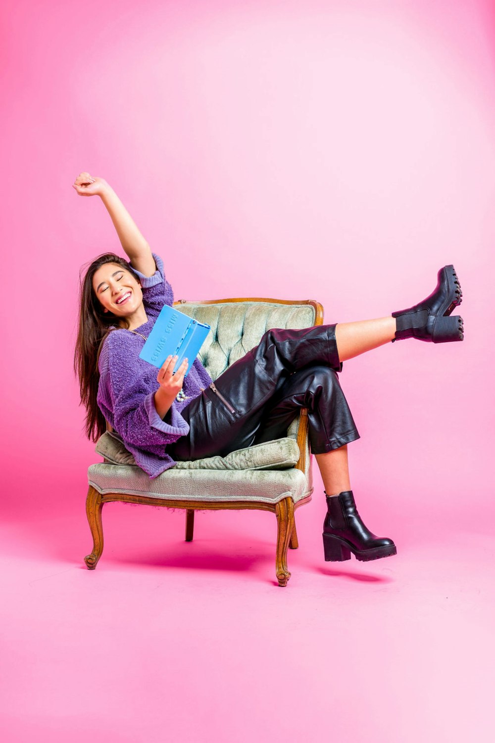 a woman sitting on a chair with a book in her hand