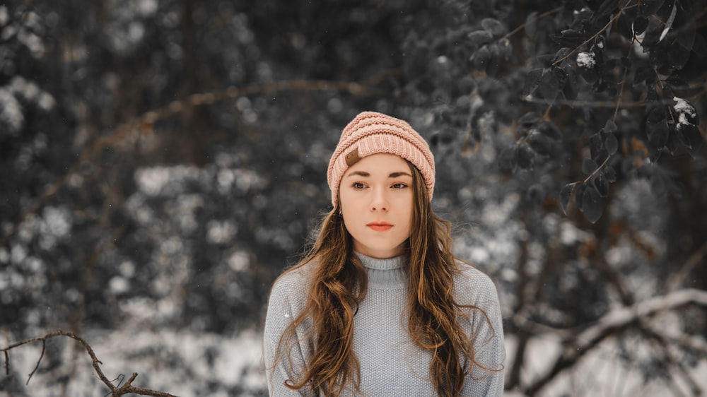 girl in white turtleneck sweater and brown knit cap standing near white leaf trees during daytime