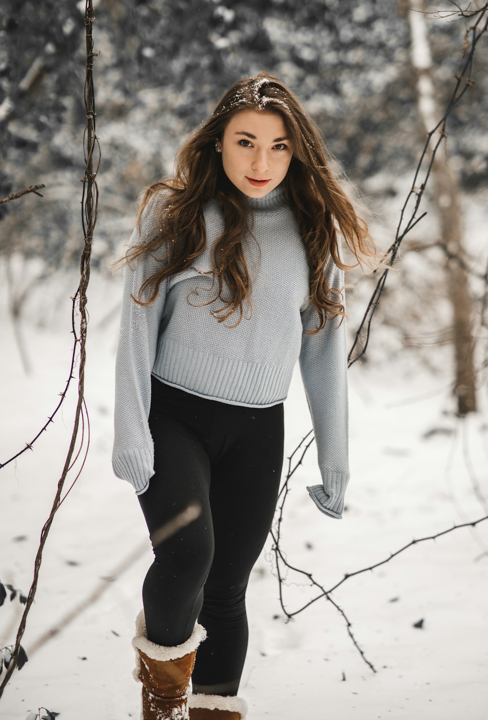 Woman in white turtleneck sweater and black leggings standing on