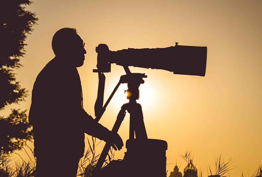 silhueta do homem segurando a câmera durante o pôr do sol