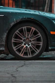 Side view of a car with muddy wheels and dirty tires before cleaning.