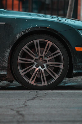 Side view of a car with muddy wheels and dirty tires before cleaning.