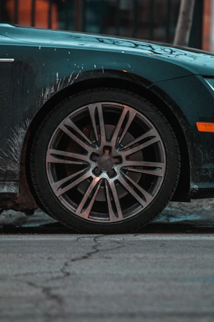Close-up of a car wheel rim covered in brake dust before and gleaming after thorough cleaning and polishing.