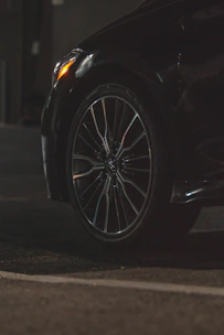 Close-up of a technician installing a tire on a sleek car in a driveway.