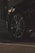 A close-up view of a car tire and wheel, featuring a sleek alloy rim. The surroundings are dimly lit, highlighting the reflective surface of the tire and part of the car body. The foreground is asphalt, suggesting the car is parked or in a driveway.