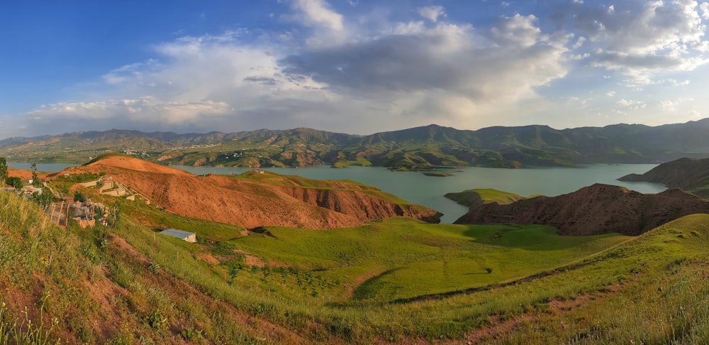 green and brown mountains near body of water under blue sky during daytime