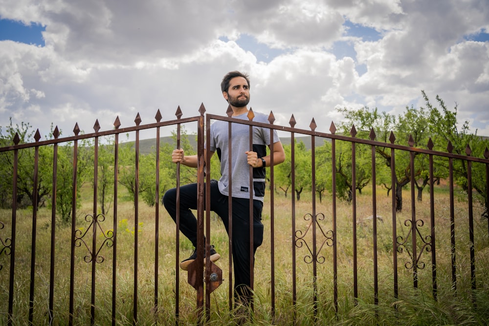 woman in white shirt and black pants sitting on brown wooden fence under white clouds during