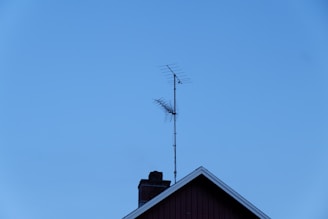 Close-up photo of a sleek outdoor antenna mounted on a building roof against a clear blue sky.