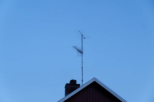 A high-quality TV antenna mounted on a rooftop against a clear blue sky