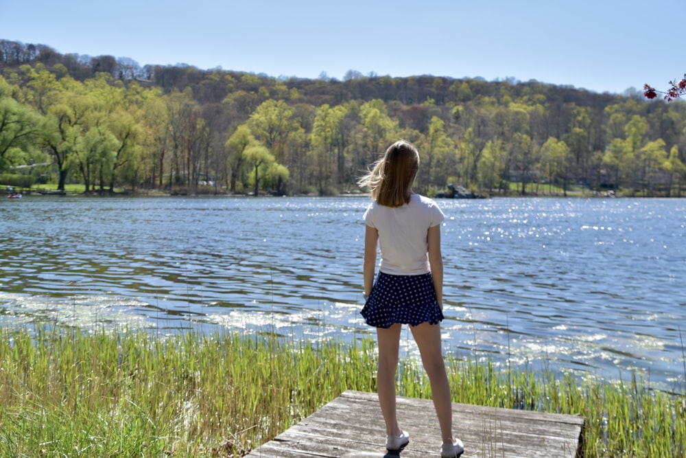 woman in white tank top and black shorts standing on dock during daytime
