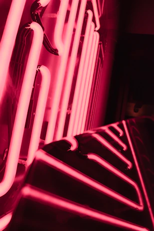 Close-up of hands carefully shaping a glowing neon sign in vibrant pink and blue hues.