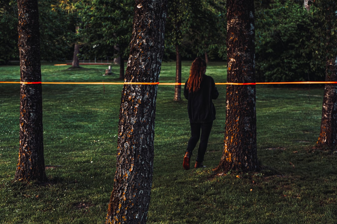 woman in black jacket standing beside brown tree during daytime