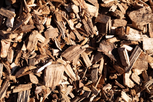 Close-up of golden wood pellets spilling from a rustic burlap sack onto a wooden surface.