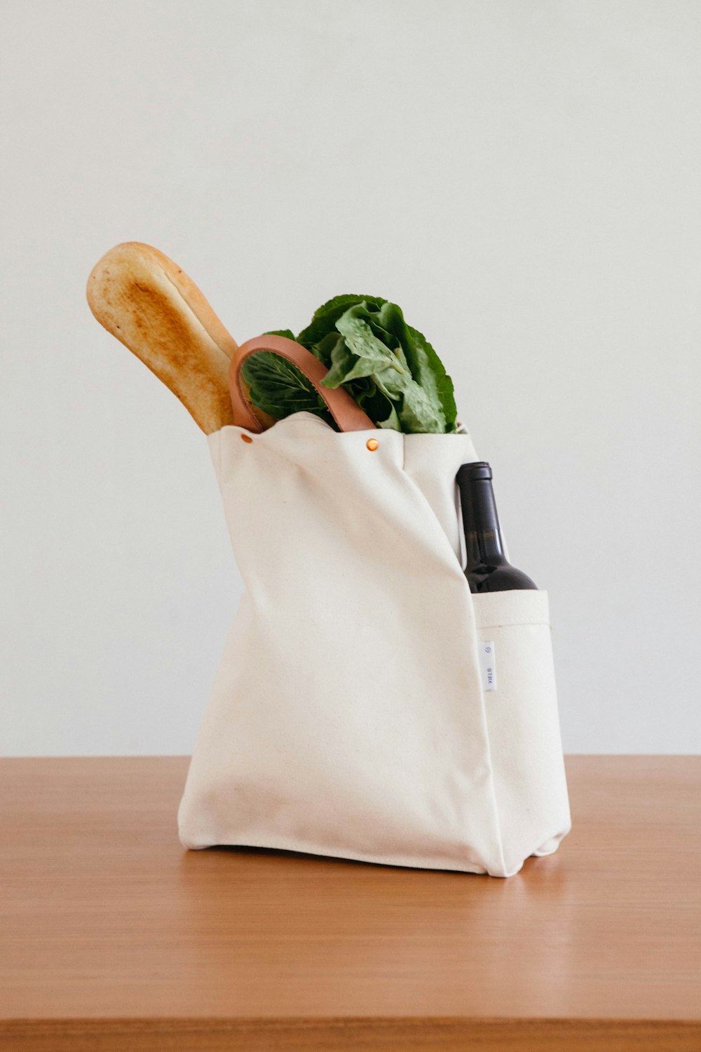 Rouleau à pâtisserie en bois brun à côté du sac en papier blanc