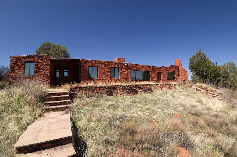 brown brick house near green grass field under blue sky during daytime