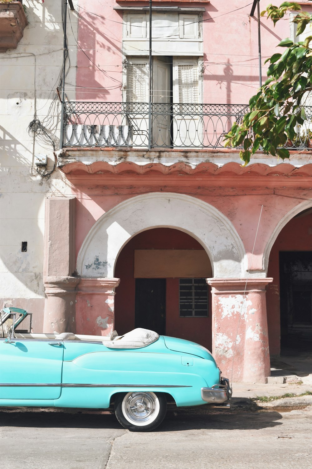 carro azul estacionado ao lado de edifício de concreto marrom e branco durante o dia