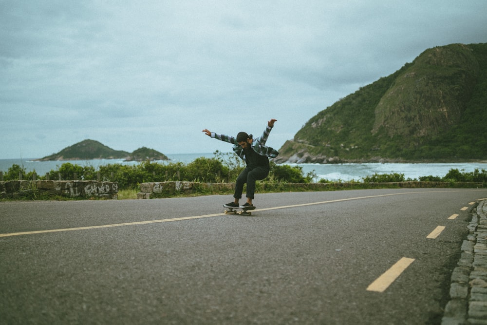 man in black jacket and black pants jumping on gray asphalt road during daytime