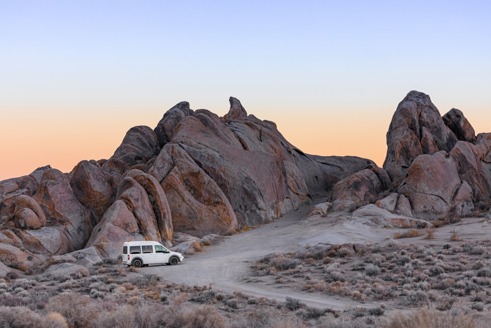 Auto bianca su sabbia grigia vicino alla formazione rocciosa marrone durante il giorno